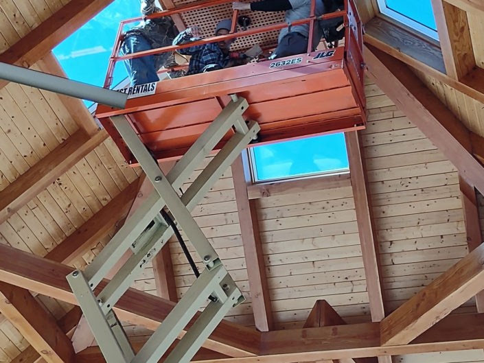 Workers installing cupola vent into interior ceiling peak in Stallings Pavilion